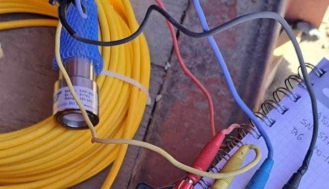 Planta-Pellets-12 Equipo de medición portátil con varios cables de colores conectados a una caja negra etiquetada "rockexam.com" y un carrete de cable amarillo junto a una libreta.
