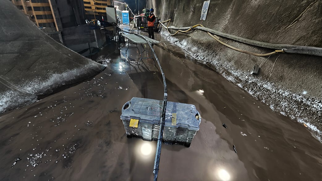 extensometros_5 Caja herramienta azul vieja con manchas y cinta, parcialmente sumergida en agua oscura con un cable negro encima.